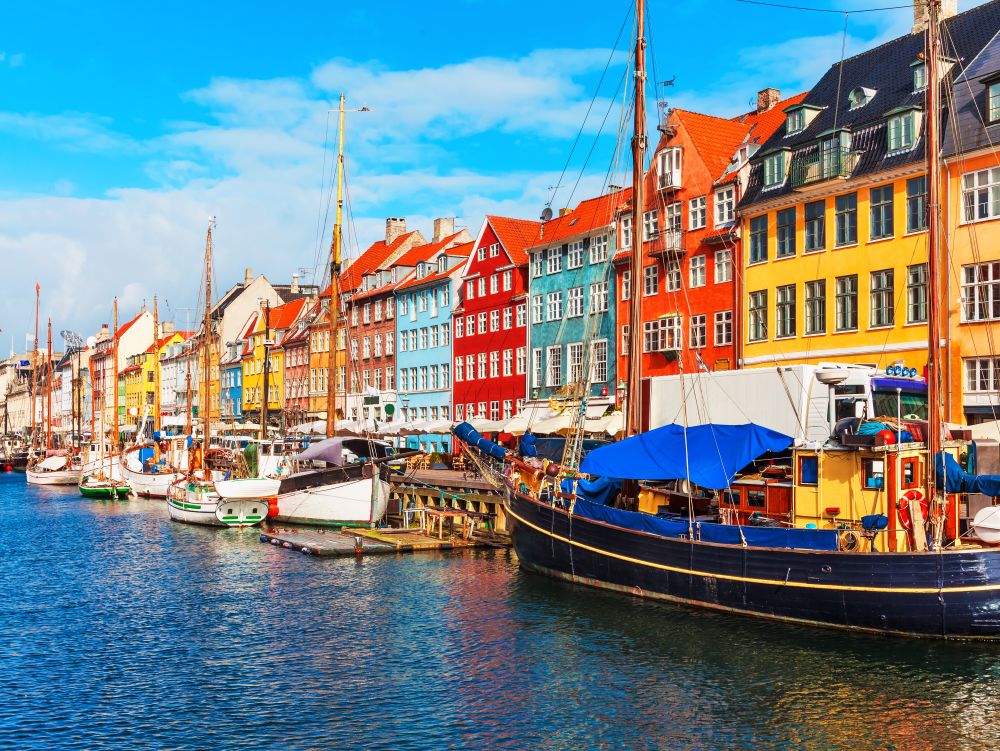 Scenic summer view of Nyhavn pier with color buildings, ships, yachts and other boats in the Old Town of Copenhagen, Denmark